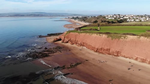 Aerial Of Orcombe Cliffs Coastline In Exmouth With Visitors On Beach On Sunny Day. Dolly Forward Sl