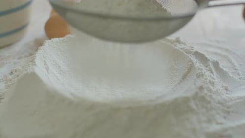 Close-Up of Sifting Flour on Kitchen Table before Dough Preparation