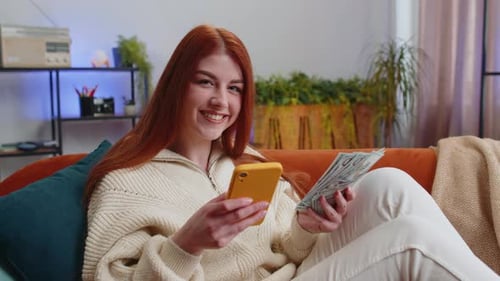 Woman Uses Smartphone While Holding Money at Home