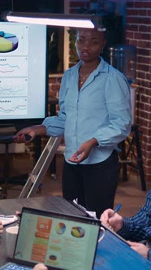 Woman Presenting Data Report to Colleagues at Night