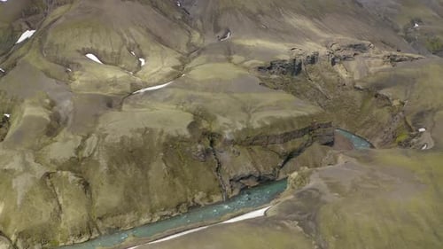 A drone shot over a river in the highlands of Iceland cutting through a valley in a canyon. Slow mot