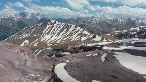Aerial panoramic view of stunning continuous mountain range partially covered with snow. Bright blue