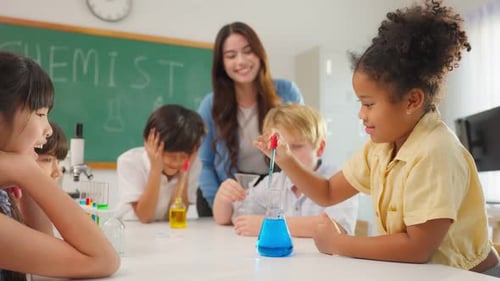 Adorable student learn with teacher in classroom at elementary school.