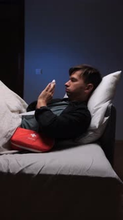 Sick Man Lies in Bed with First Aid