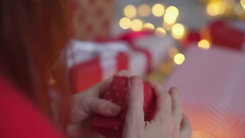 Woman Untying Small Christmas Gift at Home