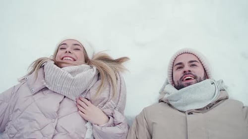 Loving Couple Smiling Lying Down in the Snow