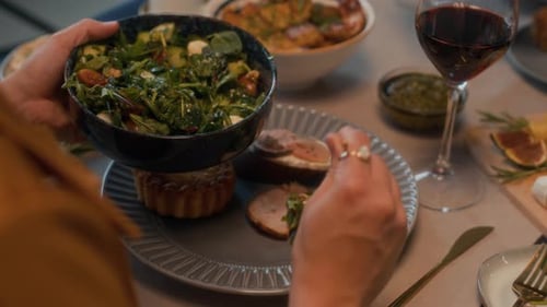 Putting Green Salad on Plate at Festive Dinner with Friends