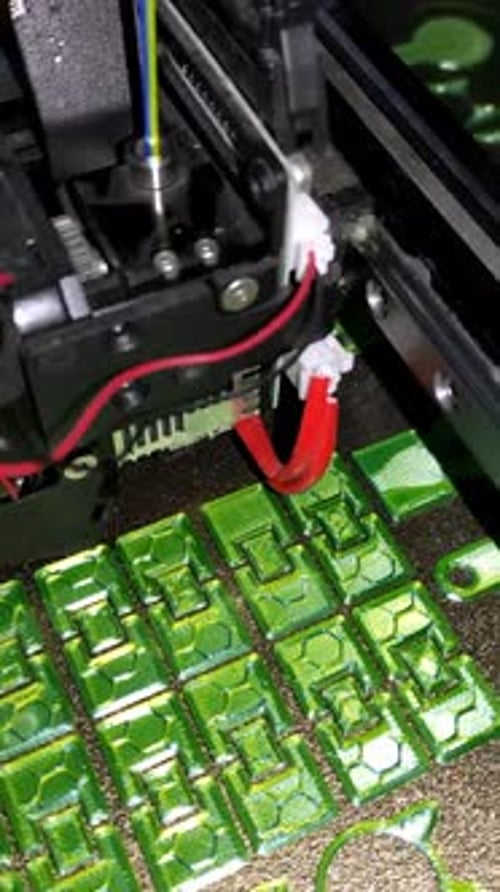 Vídeo de primer plano de la boquilla de una impresora 3D que crea coloridos objetos de plástico verde con texturas intrincadas