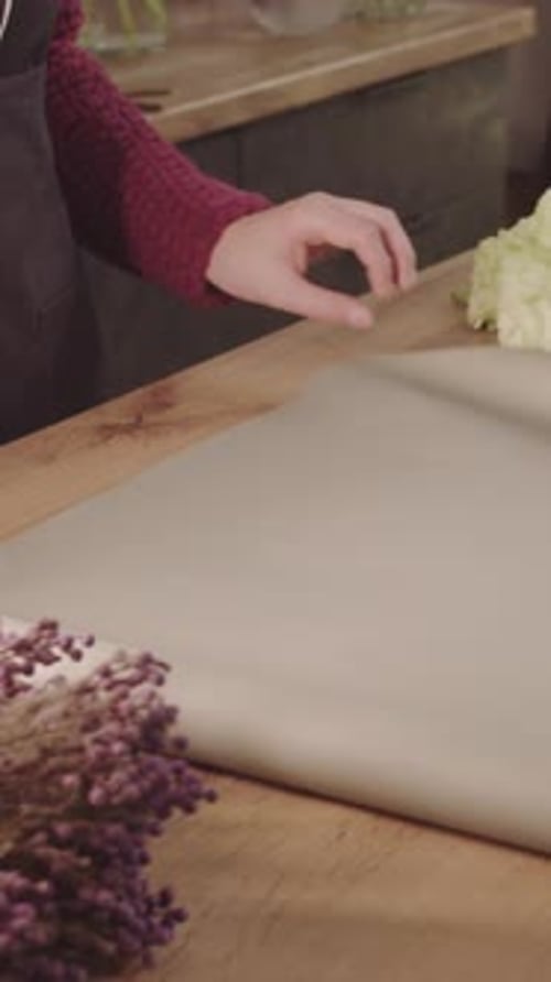 Woman Prepares Paper to Wrap Flowers at Home