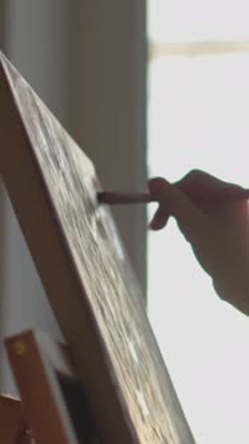 Artist Painting with Brush on Easel in Studio