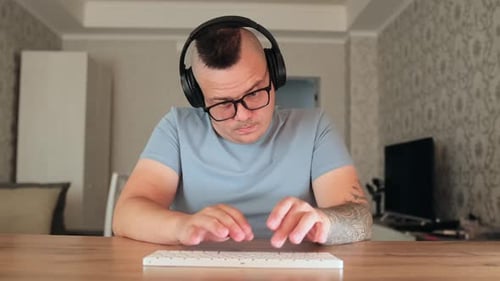 Man Typing at Keyboard Wearing Headphones