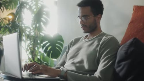Young Adult Typing on Laptop at Home
