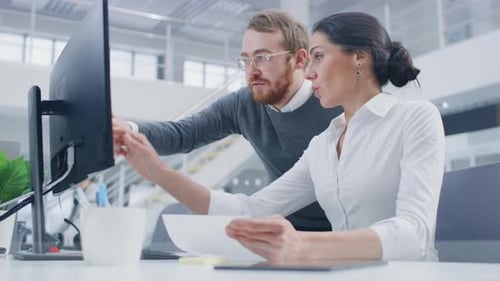 Colleagues working together at computer in modern office