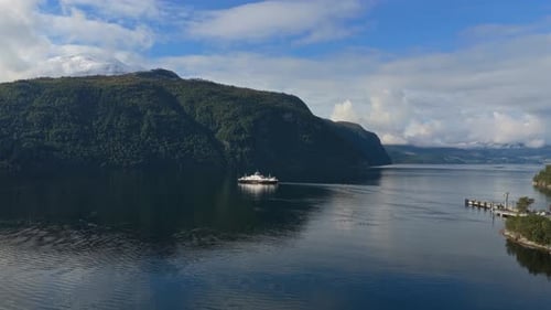 Ferry nears Eidsdal village from above, seen on calm fjord in Norway
