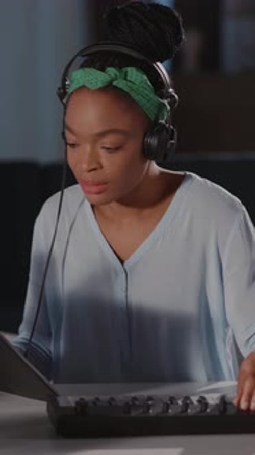 Woman Plays Keyboard Wearing Headphones Indoors at Night