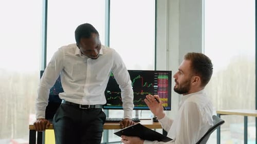 Deux traders de crypto-monnaies font une analyse professionnelle d'un graphique en chandeliers, créant une stratégie avec un stylo