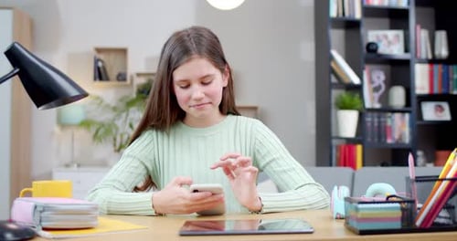 Girl at Desk Using a Mobile Phone