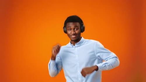 Positive Young African Man Listening to Music with Headphones in Studio