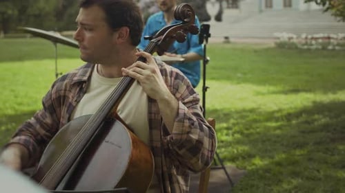Cellist Playing Cello in a Grassy Park