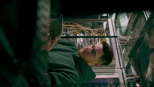 Hacker or engineer in data center holding tablet steals software or checks information from server