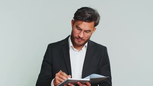 Man in Suit Writes in a Notebook