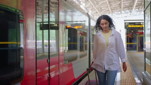 Woman Traveler Pulling Suitcase Along Train Platform