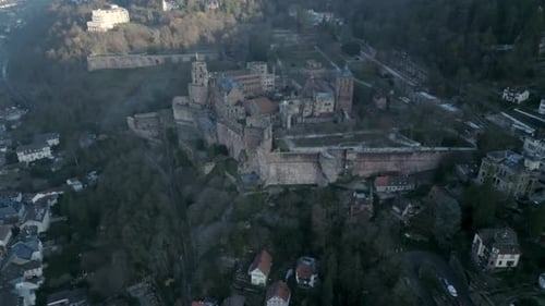 Aerial view a gothic castle sitting atop a hill of a remote village in Europe