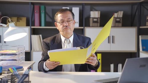 Frustrated Businessman Contemplates a Document at Desk