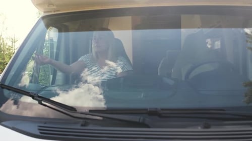 Adult lowers shade in RV camper on road trip