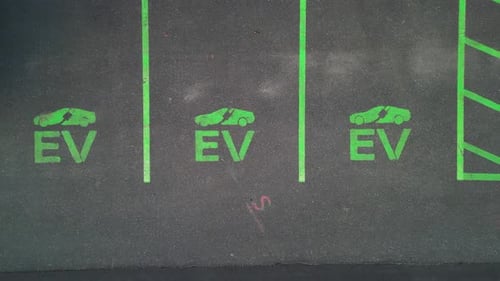 Cars and parking area with EV Electric Vehicle lots in american town. Aerial top down flyover. Moder