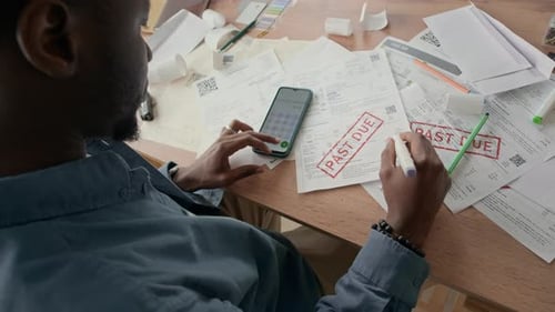 Man Using Smartphone Calculator While Organizing Household Expenses