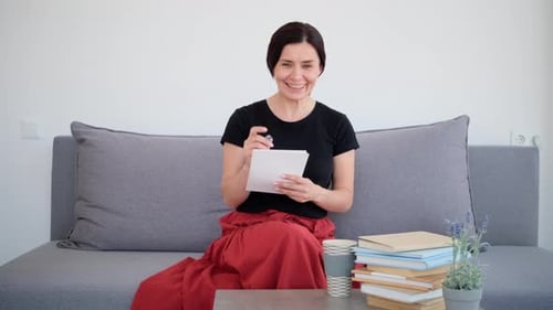 Woman Sits and Writes Notes at Home