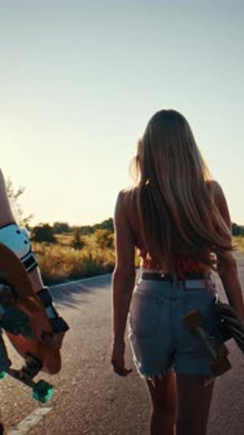 Young Women Stroll Together Along Rural Road During Sunset