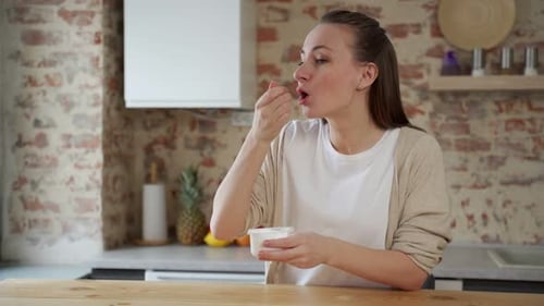 Happy Woman Enjoying Yogurt in Kitchen