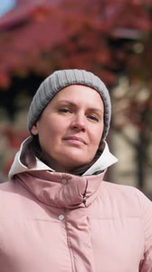 Femme confiante souriant à l'extérieur en automne sous un ciel lumineux