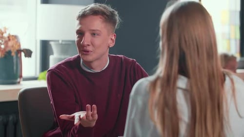 Young Man Talking at a Table Indoors