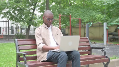 Man Works on Laptop in Urban Park Setting