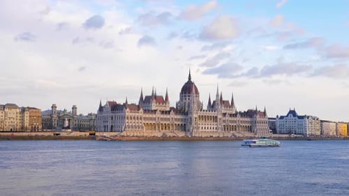 Yacht sailing along the Danube river in front of the Hungarian Parliament building. Golden hour. Bud