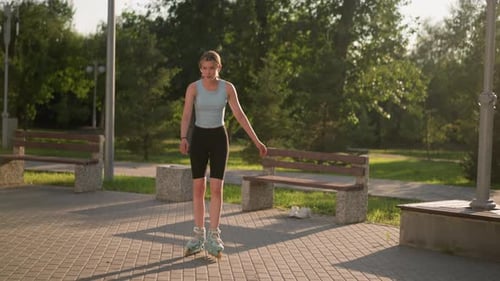 Young Lady Skating Outdoors in Park Surrounded By Greenery and Benches