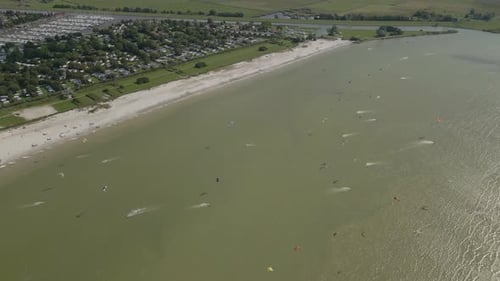 Aerial view of people doing kite surfing along the beach sunny day, Netherlands