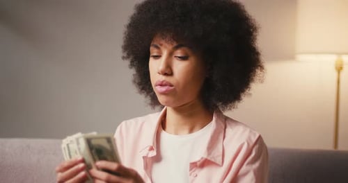 Young Woman Counting United States Currency Indoors