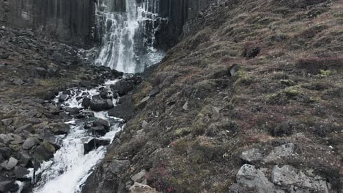 Reveal shot of Svartifoss waterfall, showing its imposing columns and its size, drone shot