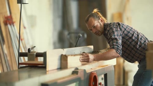 Carpenter Planing a Wooden Beam in a Workshop