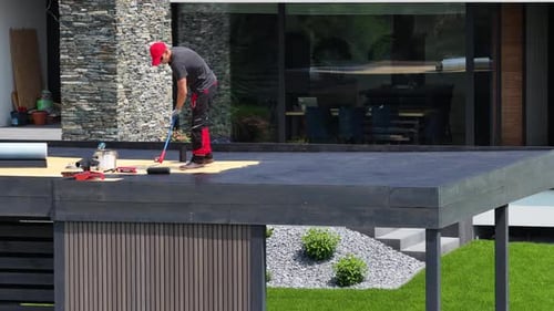 Roofer Installing EPDM Material on Modern Flat Roof in Residential Area During Daylight Hours
