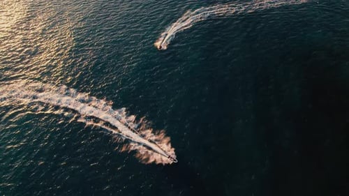 Jet Skis Speeding Across the Ocean at Sunset