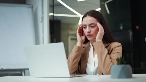 Tired Female Manager Having Migraine While Working on Laptop at Office