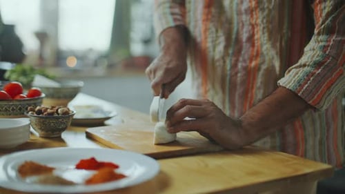 Un blogueur culinaire indien découpe du fromage Paneer en cuisinant à la table de la cuisine