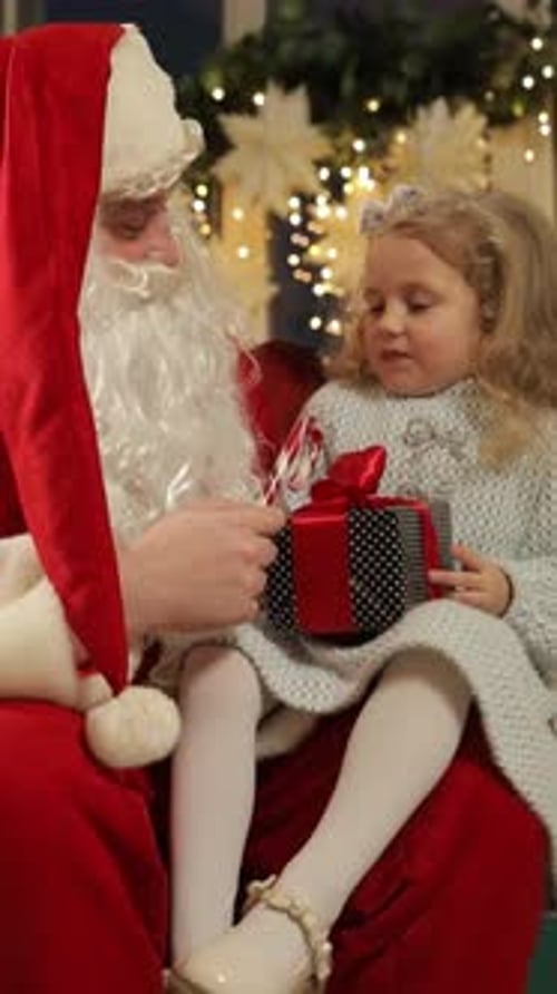 Little Girl Receiving Christmas Gift from Santa Claus