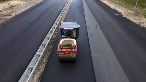 Road roller compacts and levels the new hot asphalt. Pavement repair technology