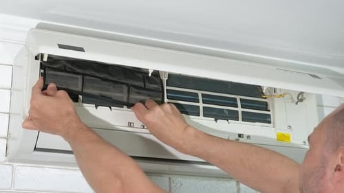 Man Replacing Dirty Air Conditioning Filter Indoors
